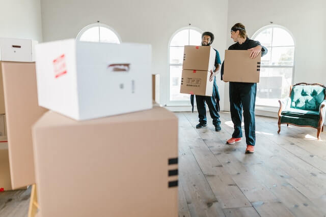 Ventajas del financiamiento de muebles representado como dos repartidos entregando cajas en una habitación vacía